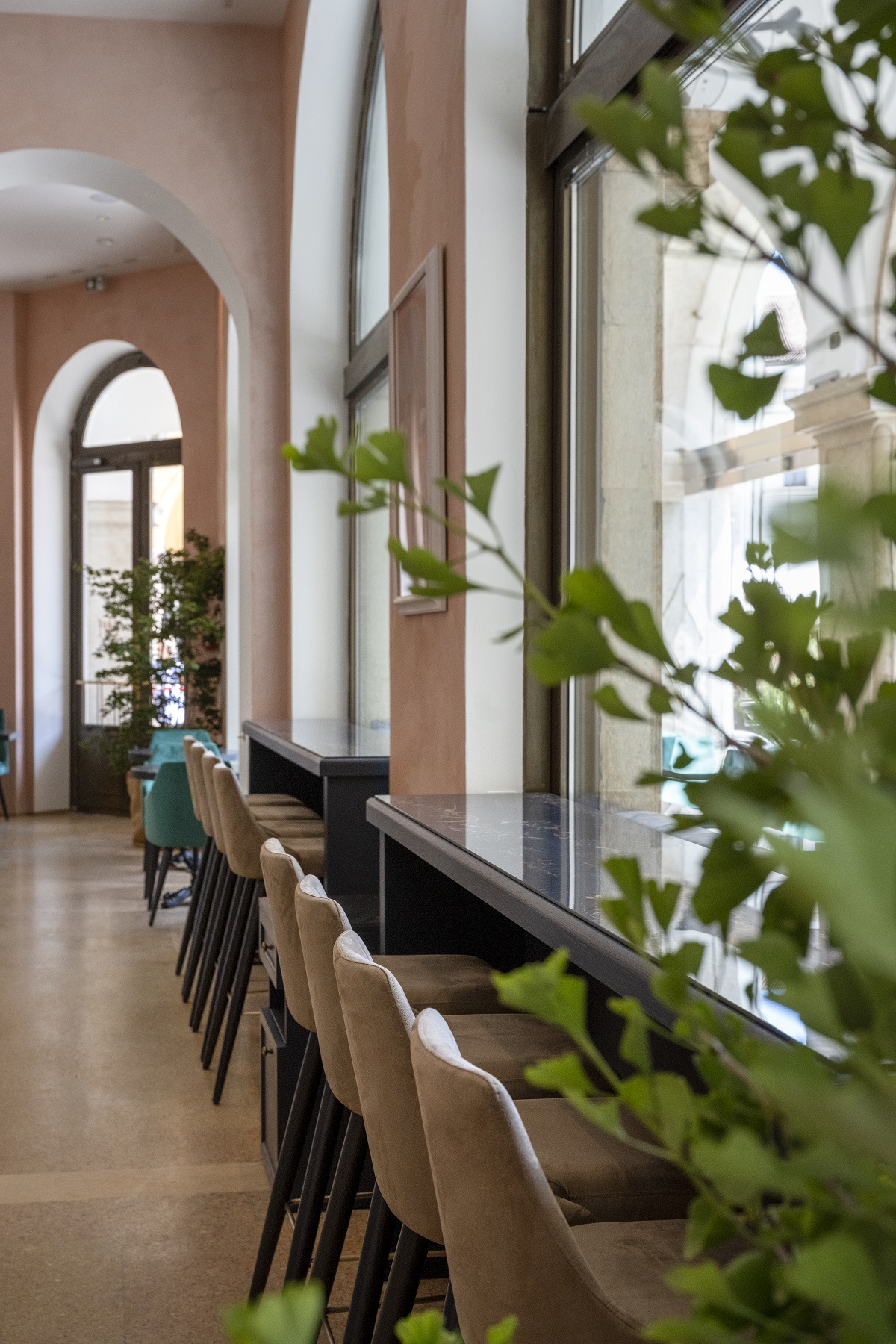 plants, stone floors and soft greens and browns in the cafe at Stadt Hotel Citta