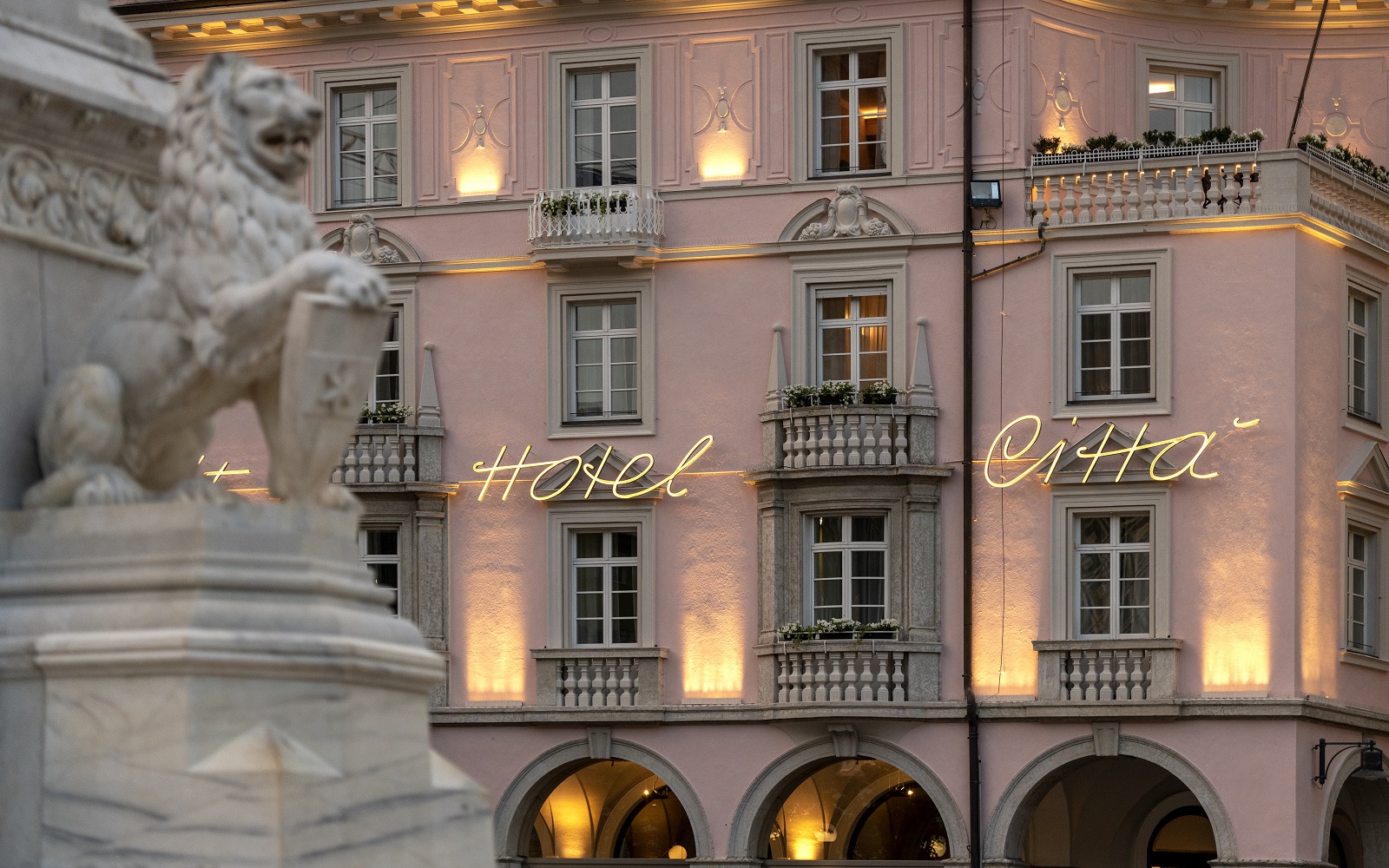 the pink and grey turn of the century style facade of Hotel Citta with marble statue in foreground