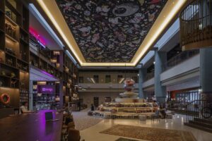 central lobby in 25hours Dubai with futuristic lighting on the ceiling and a central feature book tower