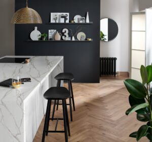 herringbone design wood parquet flooring in kitchen with marble surfaces and dark background wall