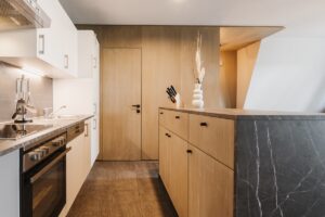 galley kitchen in apart-hotel with wood and black marble surfaces