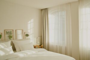 filtered light in white and cream guestroom with white linen and pictures behind the bed