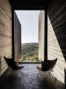 2 butterfly chairs positioned between two walls with floor to ceiling view across cypriot landscape