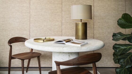 wooden chairs around a stone coloured organic shaped table in front of natural raffia textured wallcovering from Arte