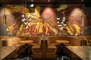 strong visual design with an organic mural and strong architectural lighting in restaurant designed in shades of yellow and brown