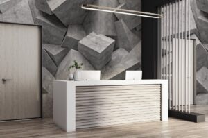 white rectangular reception desk in front of wallcovering of oversized concrete blocks in shades of grey