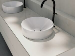 detail of minimalist round countertop BetteSuno basin with black tap in a row on a cream bathroom countertop