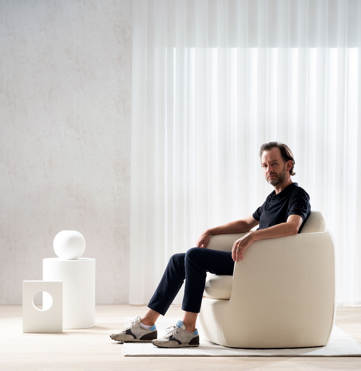 designer Tim rundle seated in white Bilbao chair in white room setting