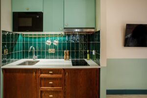 view onto the kitchen galley in hometel room2 with dark green tiles and wooden surfaces