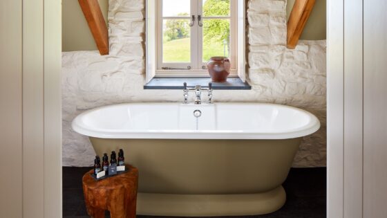 roll top bath in front of window in beamed country bathroom