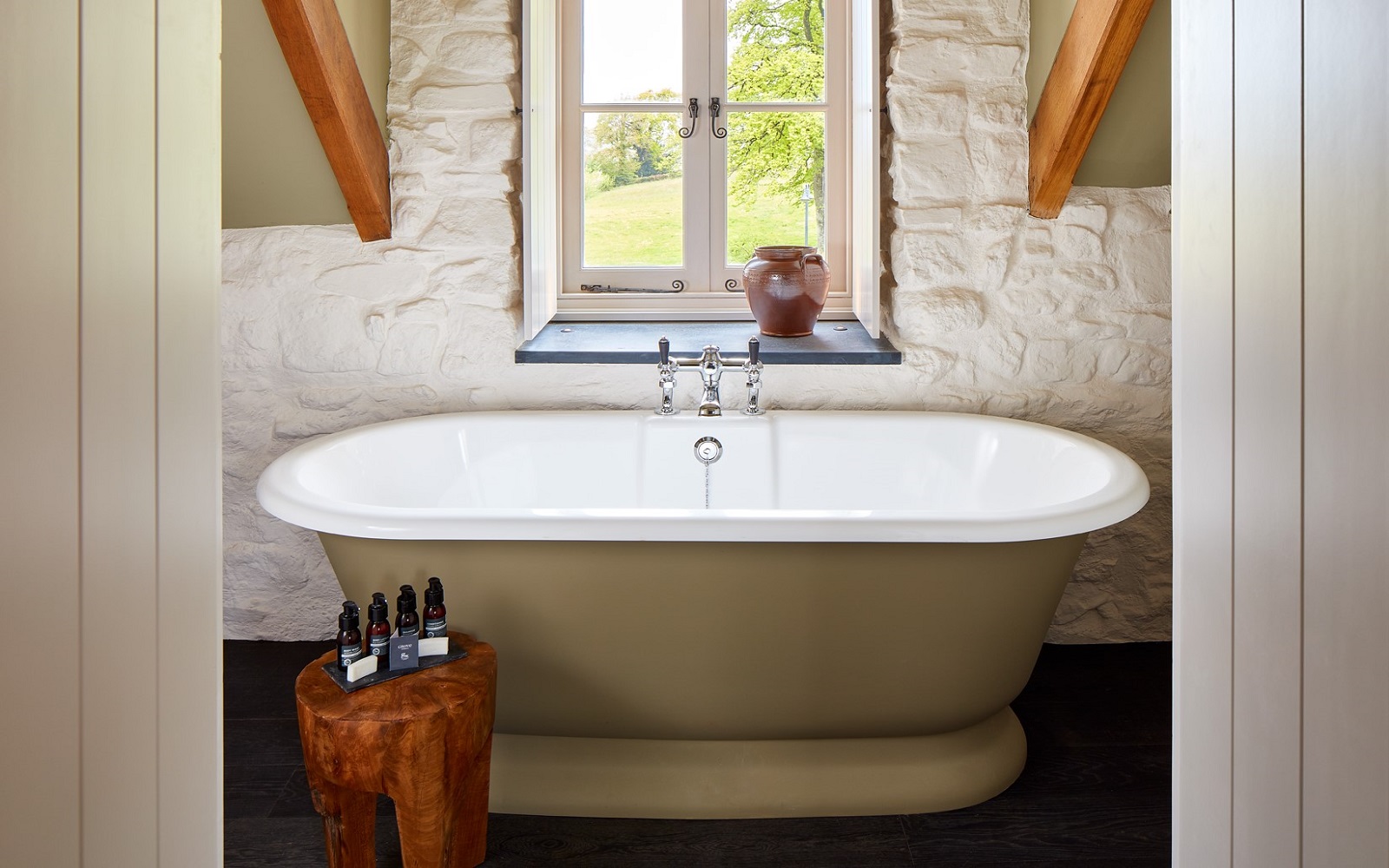 roll top bath in front of window in beamed country bathroom