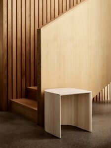 wooden tabouret stool against wood panel in front of wooden staircase