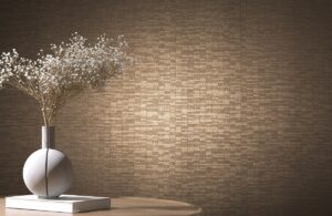 textured brown wallcovering behind simple cream vase with delicate flowers on top of a white book on a wooden table