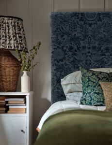 upholstered headboard in dark green patterned Morris 7 co velvet fabric and patterned velvet cushions on the bed