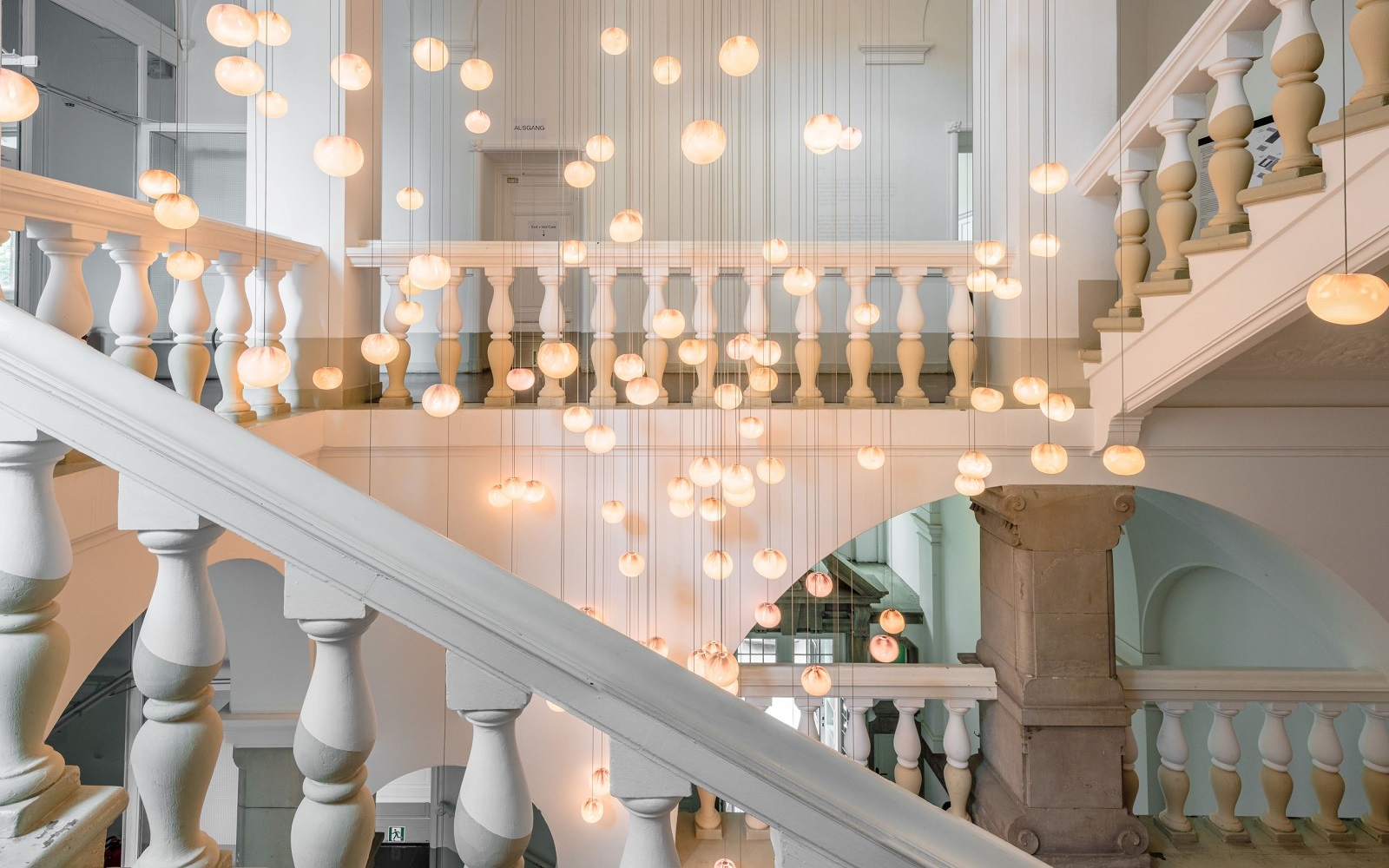 interior hallway and stairway of Wilmina hotel in white and cream with statement hanging lights in the centre