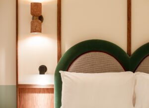 detail of bedroom with green velvet detail on headboard and handmade ceramic wall lights