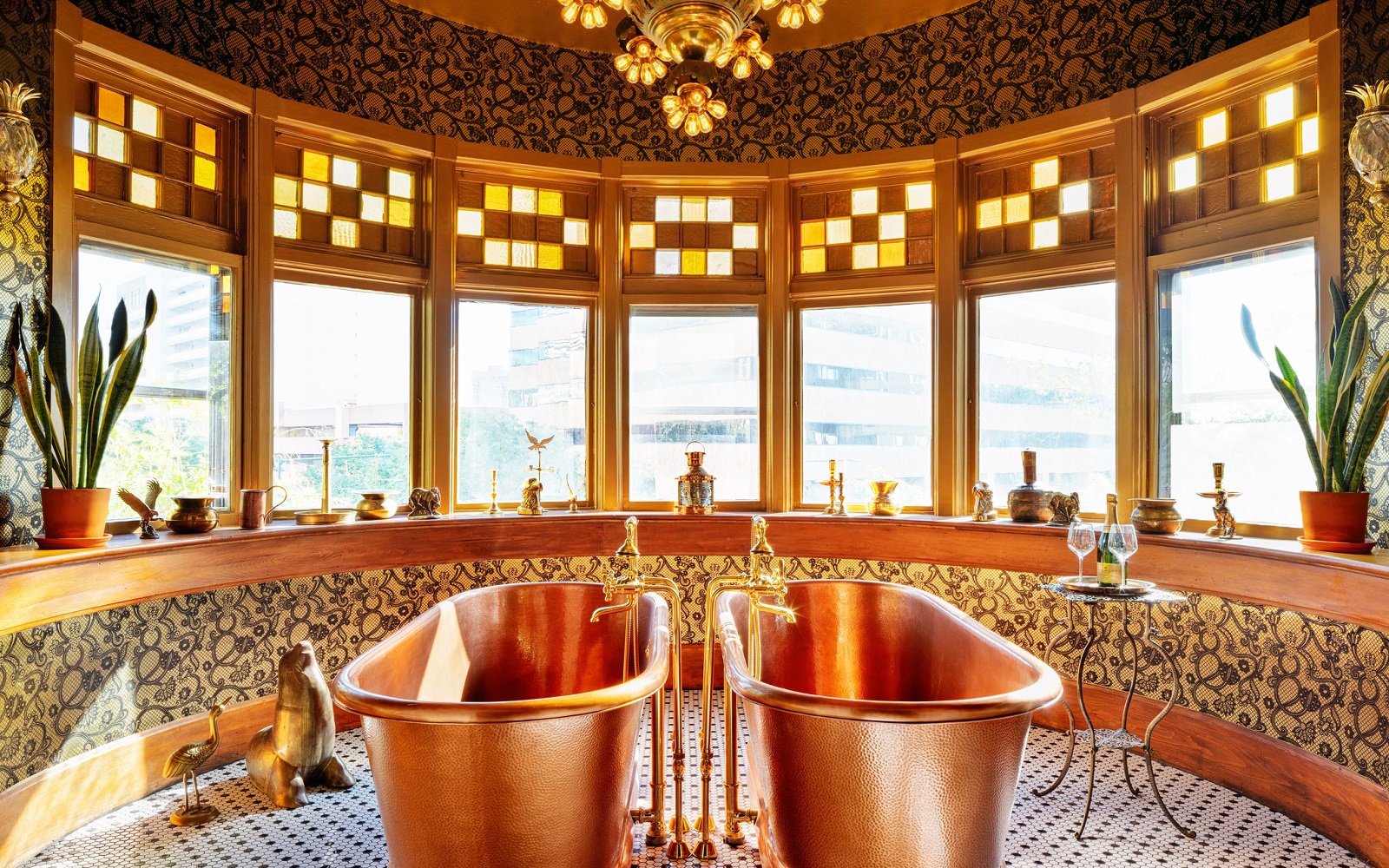 two freestanding copper baths in front of rounded windows with stained glass detail and view across denver