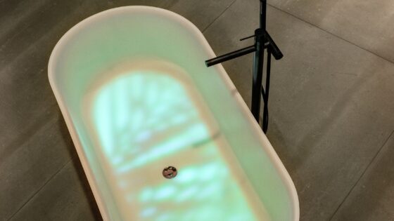 freestanding bath with light reflections in the water and black pillar tap