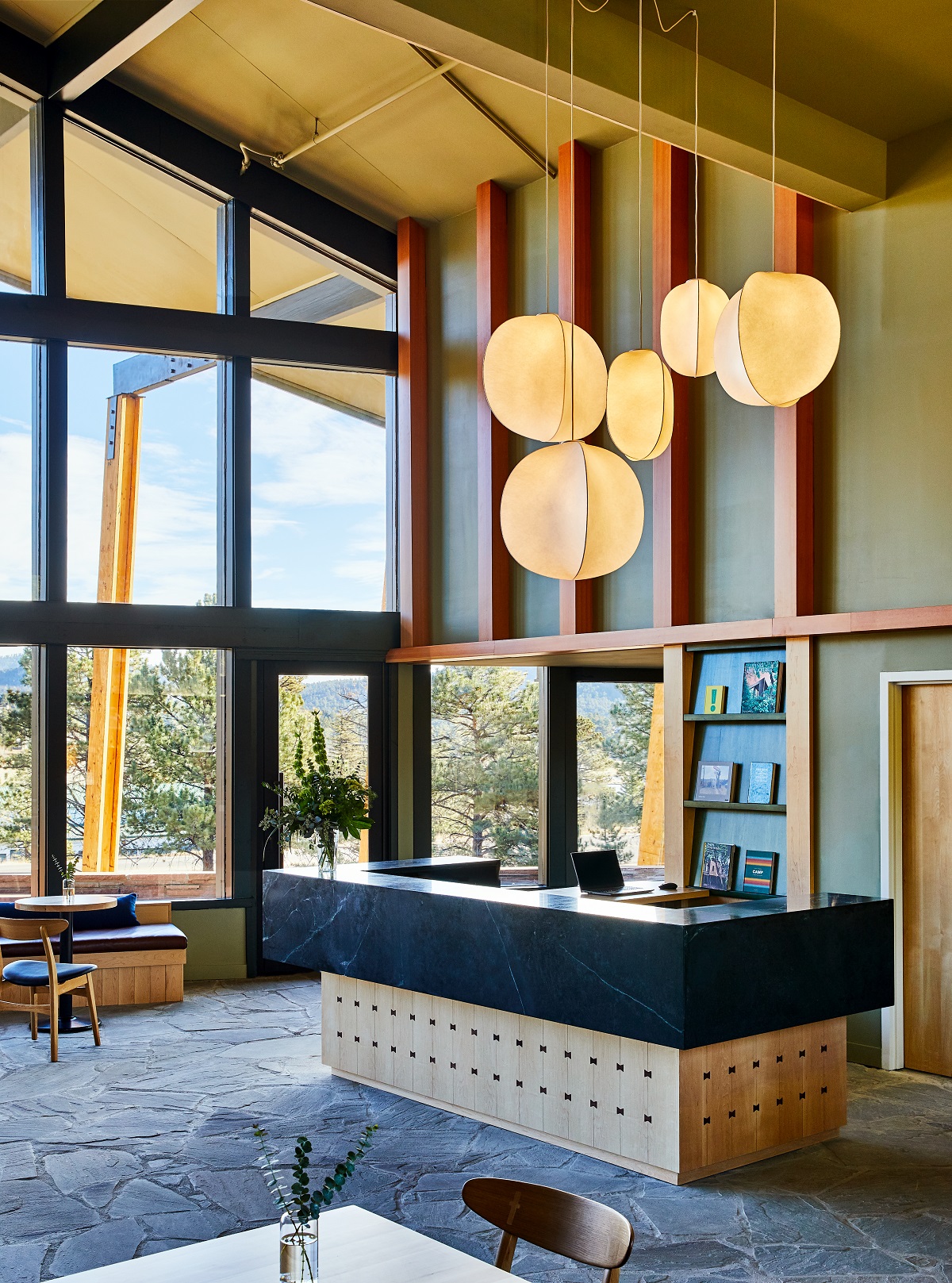 wooden framed lobby with floor to ceiling windows and pendant lights above wooden front desk