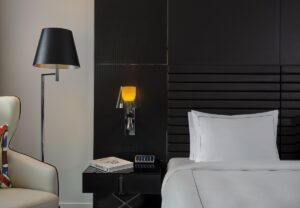 chair, bed and floor lamp against black headboard in art'otel London Hoxton