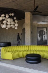 curved acid yellow couch on concrete floor in safari lodge Angama Amboseli