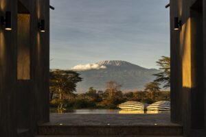 view through open doors across infinity pool at safari camp across to mt Kilimanjaro