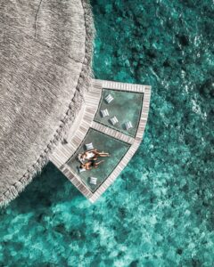 view from above of thatched roof and bathing platfrom over the water at Raffles Maldives Meradhoo