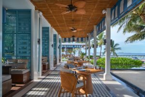 louvred terrace with blue shutters under a wicker ceiling with fans at Raffles Maldives Meradhoo