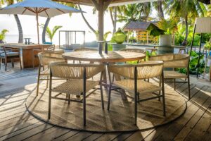 rattan chairs around table under umbrella at pool bar on a wooden deck