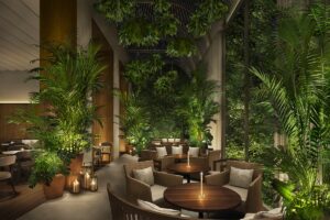 planted tropical wall, wooden dining tables and candlelight in the Singapore EDITION