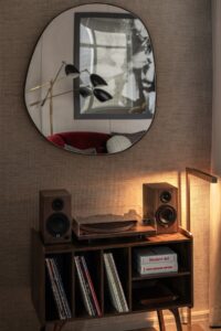 irregular round mirror above retro record player and record collection