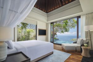 seaview from bed in villa with draped curtain and floor to ceiling glass doors and windows