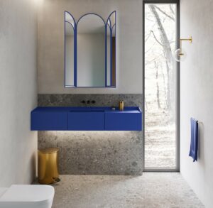 blue basin and vanity unit against stone wall next to floor to ceiling window in bathroom with Unidrain Reframe fittings