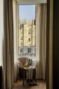 chair in a hotel window overlooking historic buildings in Milan