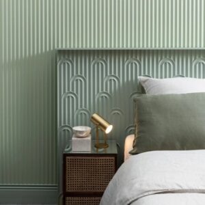 green textured wall panels behind bed with white linen and green cushion