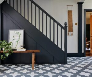 black and white floor tiles in hallway with black wooden staircase