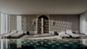 blue tiled indoor pool with sunlight on stone coloured walls and sunloungers