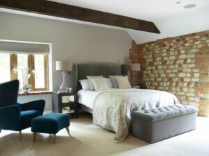 double bed in guestroom with wooden beam and exposed brick wall