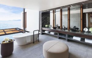 freestanding white bath in front of glass wall with ocean view