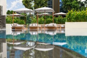 outdoor pool with reflections of parasols at Conrad Singapore Orchard