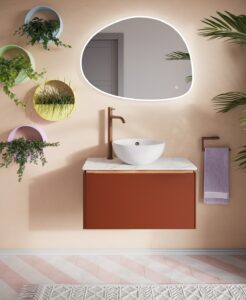 pebble shaped backlit mirror from Crosswater above single basin and vanity with plants on the wall