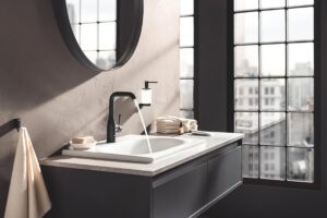 black bathroom tap below round mirror on wall hung vanity unit