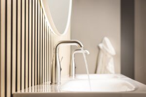 Essence basin mixer from GROHE against wood panelled surface in natural bathroom design
