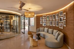 curved rammed earth wall behind curved couch and carved wooden chairs