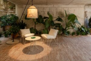traditional brick floor and concrete walls with plants and patio furniture under organic lighting feature in Hotel Pátio do Tijolo