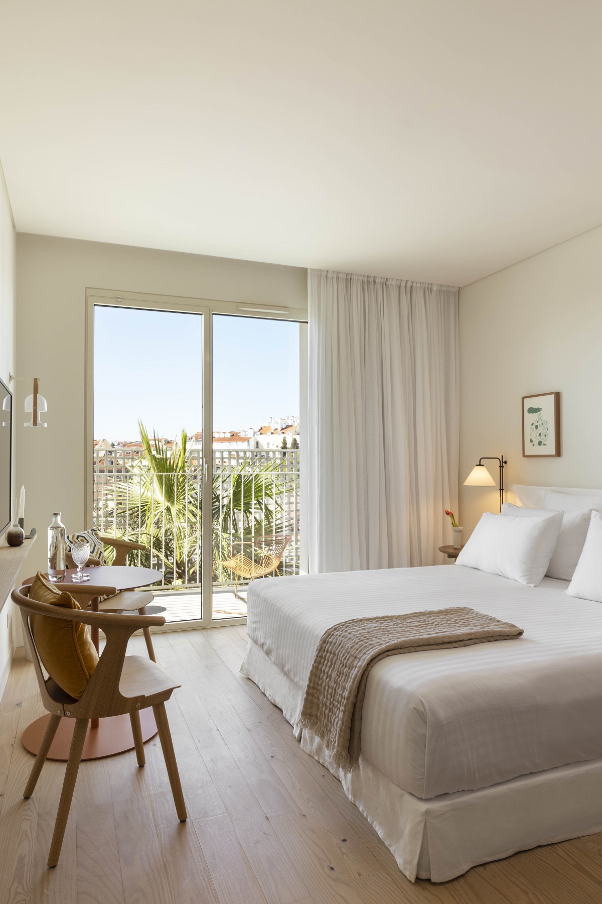 white bedroom interior with wooden chair and view over Lisbon