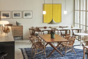 wooden dining table on blue moroccan carpet with abstract yellow painting on the wall