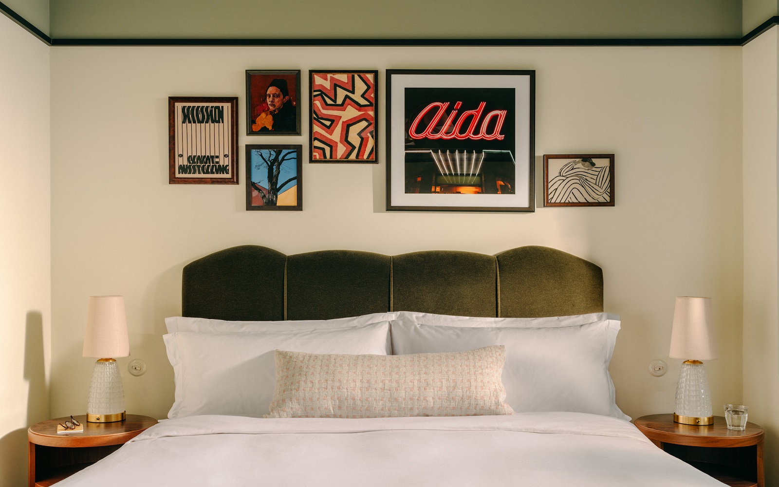 guestroom in The Hoxton Vienna with velvet upholstered headboard and art gallery on the wall