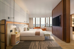 double bed on striped carpet in front of wooden divide and floor to ceiling windows in boca Raton tower