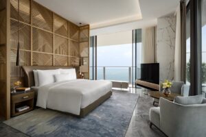 wooden screen behind hotel bed with doors leading onto terrace and seaviews
